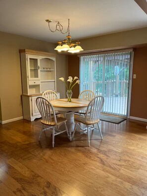 A dining area with a round table, white chairs, a chandelier, and a cabinet with glass doors. - Country Knoll 4/2 with 6 beds (Saint Charles)