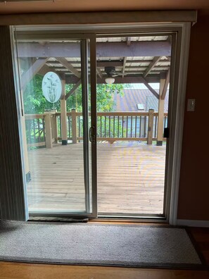A sliding glass door leading to a wooden deck with a view of a house and trees. - Country Knoll 4/2 with 6 beds (Saint Charles)