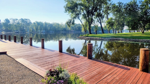 Une jetée en bois s’étendant dans une étendue d’eau calme, entourée d’une végétation luxuriante et d’arbres.
