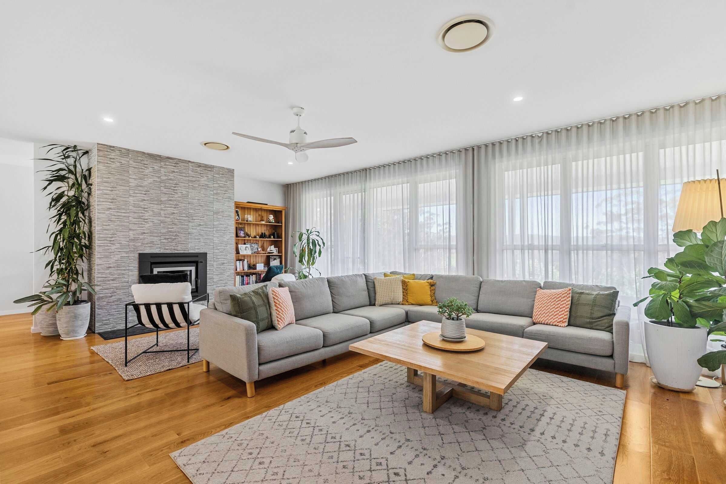 A modern living room with a grey sectional sofa, a wooden coffee table, and a fireplace.