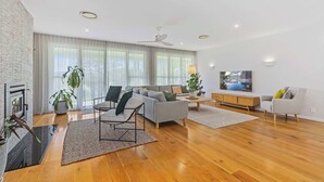 Ein modernes Wohnzimmer mit einer Couch, Sesseln, einem Couchtisch und einem Fernseher.