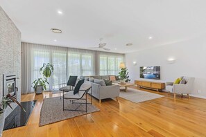 A modern living room with a sofa, chairs, a coffee table, and a TV. - Hamptons Estate: Freshwater Pool, 8 Mins Beach (Terrigal)