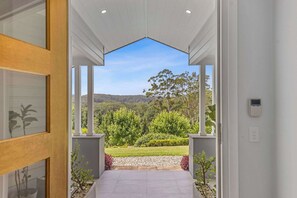 A modern hallway with a view of a lush garden and hills in the distance. - Hamptons Estate: Freshwater Pool, 8 Mins Beach (Terrigal)