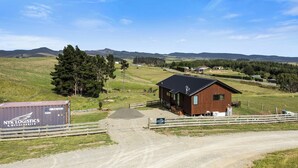 A rural setting with a wooden cabin, a gravel road, and a shipping container labeled 'NYK LOGISTICS & MEGACARRIER'.