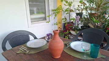 A wooden table with a terracotta vase, two plates, and two glasses.
