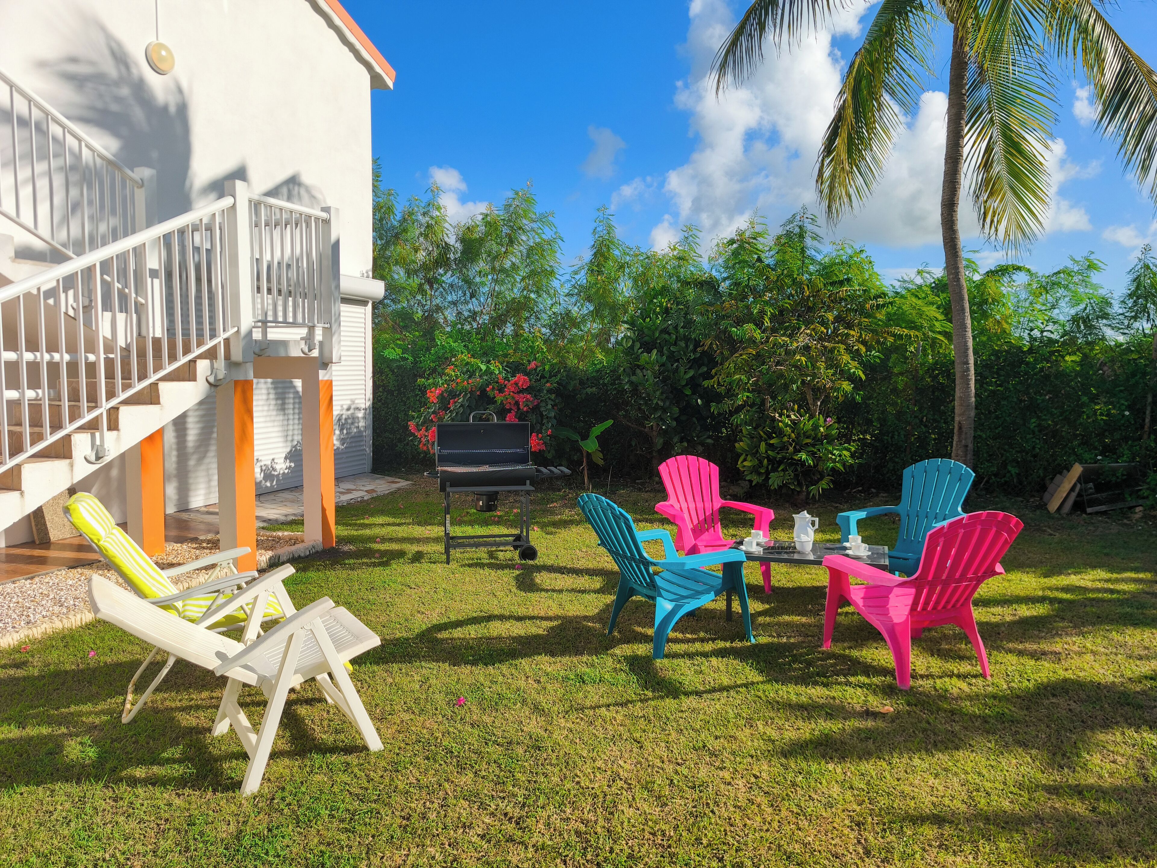 A patio with outdoor furniture, a barbecue grill, and a staircase leading to a white building.