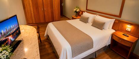 Une chambre d’hôtel avec un lit, une télévision, un magazine et une armoire en bois.