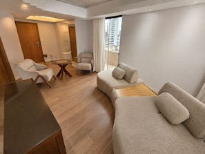 Una sala moderna con sofá, sillones, una mesa de centro y un escritorio de madera.