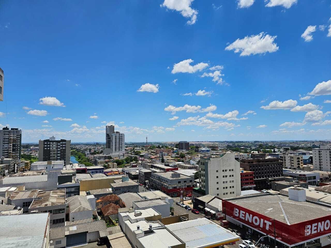 Un paysage urbain où se côtoient des bâtiments modernes et plus anciens, sous un ciel bleu dégagé parsemé de quelques nuages.