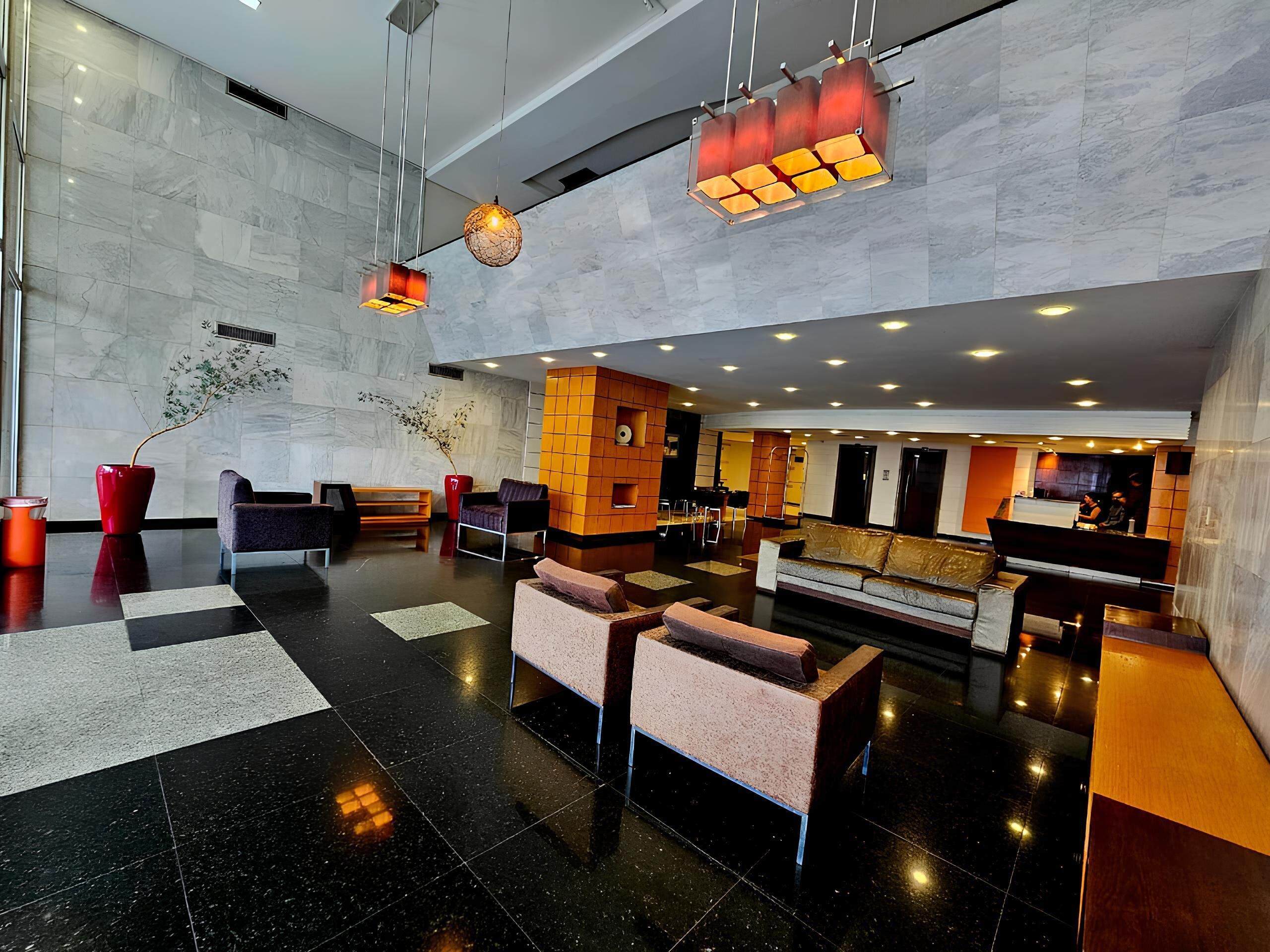 A modern lobby with a reception desk, seating area, and a marble wall.