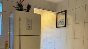 Et kompakt køkken med et hvidt køleskab, et lille bord og en sofa.