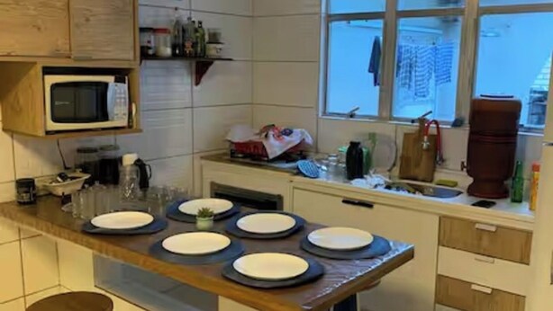 Et køkken med en central ø, barstole, en mikrobølgeovn og et vindue med udsigt.