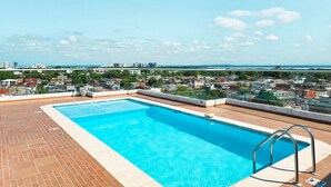 En pool på taket med fri utsikt över stadsbilden och havet i bakgrunden.