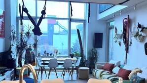 Ett modernt kök med ett stort fönster, en matplats med stolar och en soffa med kuddar.