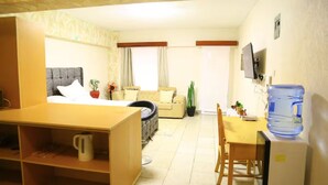 Ein kompaktes Hotelzimmer mit Bett, Sofa, Esstisch und Fernseher.