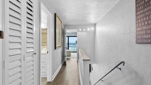 A hallway with a view to a balcony, white shutters, and a motivational quote on the wall. - Zodiac 4 (Daytona Beach Shores)