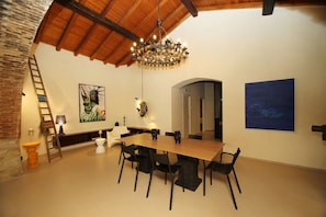 Uma sala de jantar com mesa e cadeiras de madeira, um lustre e obras de arte nas paredes.