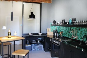 Una cocina moderna con una mesa de madera, taburetes de bar, una estufa y un salpicadero verde.