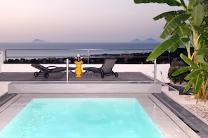 Piscina ao ar livre com duas espreguiçadeiras e um hidrante amarelo.