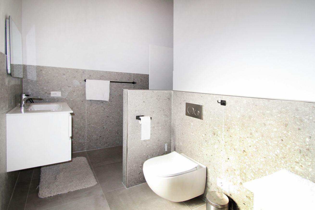 Ein modernes Badezimmer mit einem weißen Waschbecken, einer Toilette und einer Duschkabine.