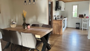 Een eethoek met een houten tafel, stoelen en een hanglamp.