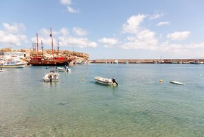 A marina with several boats docked, a large red ship, and a clear blue sky. - Aqua Vero seaside residence (Limenas Chersonisoy)
