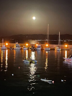 A marina at night with boats docked and a full moon in the sky. - Aqua Vero seaside residence (Limenas Chersonisoy)