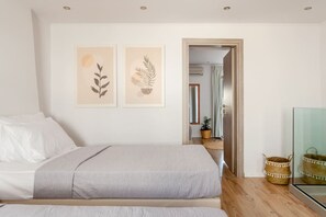 A bedroom with two beds, a wooden floor, and a door leading to a bathroom. - Aqua Vero seaside residence (Limenas Chersonisoy)