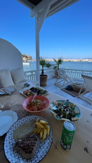 Eine Terrasse mit Esstisch mit Blick auf einen Yachthafen und Boote.