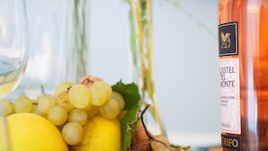 Ett bord med en flaska Castel del Monte-vin, en tallrik med druvor och citroner samt ett glas vitt vin.