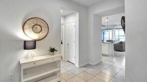 A modern hallway with a white console table, a decorative mirror, and a potted plant. - Lakefront 5BR Villa • Private Pool near Disney (Kissimmee)