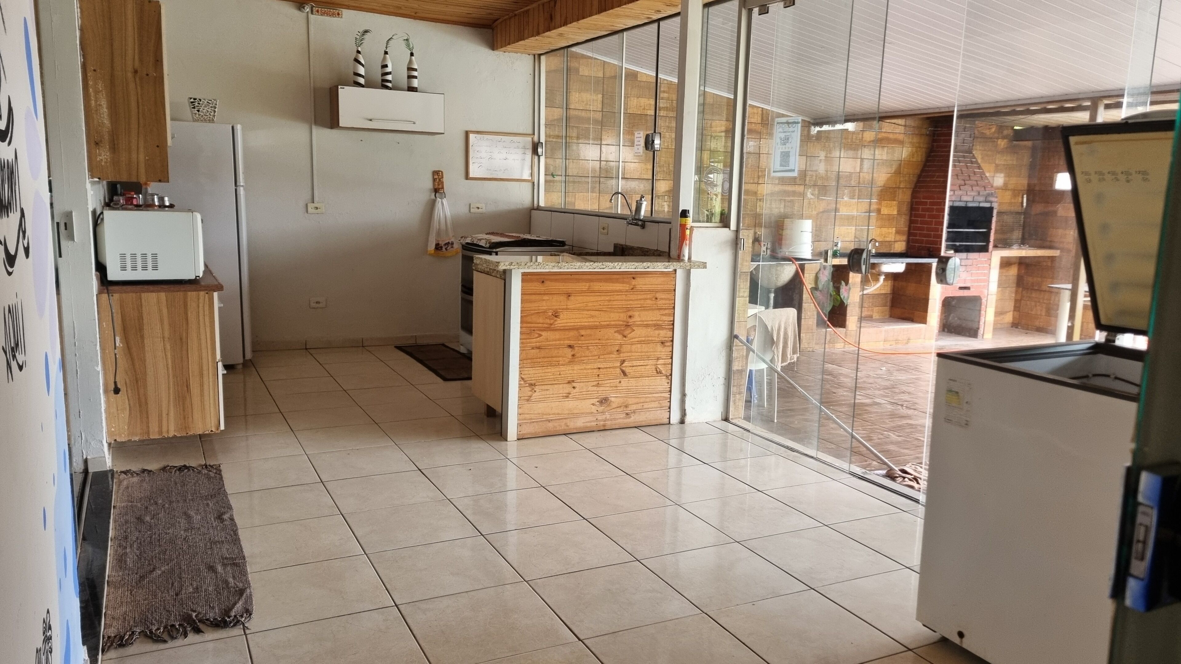 Een moderne keuken met een houten kookeiland, een koelkast en een raam met uitzicht op een terras.