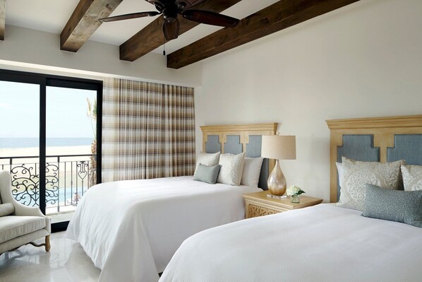 Une chambre d’hôtel avec deux lits, un balcon avec vue et un ventilateur de plafond.