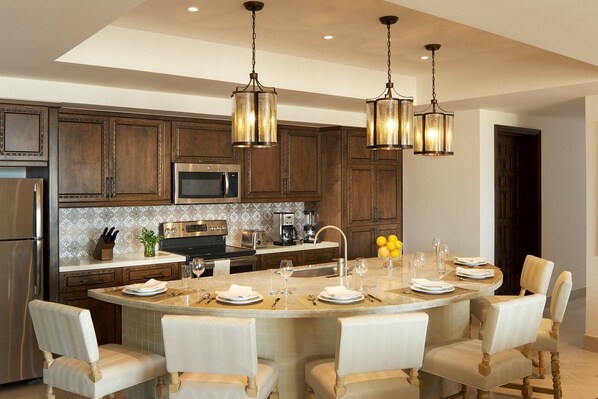 A modern kitchen with dark wooden cabinets, stainless steel appliances, and a central island with seating.