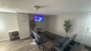 Een woonkamer met een flatscreen televisie, twee banken, een salontafel en een bijzettafeltje.