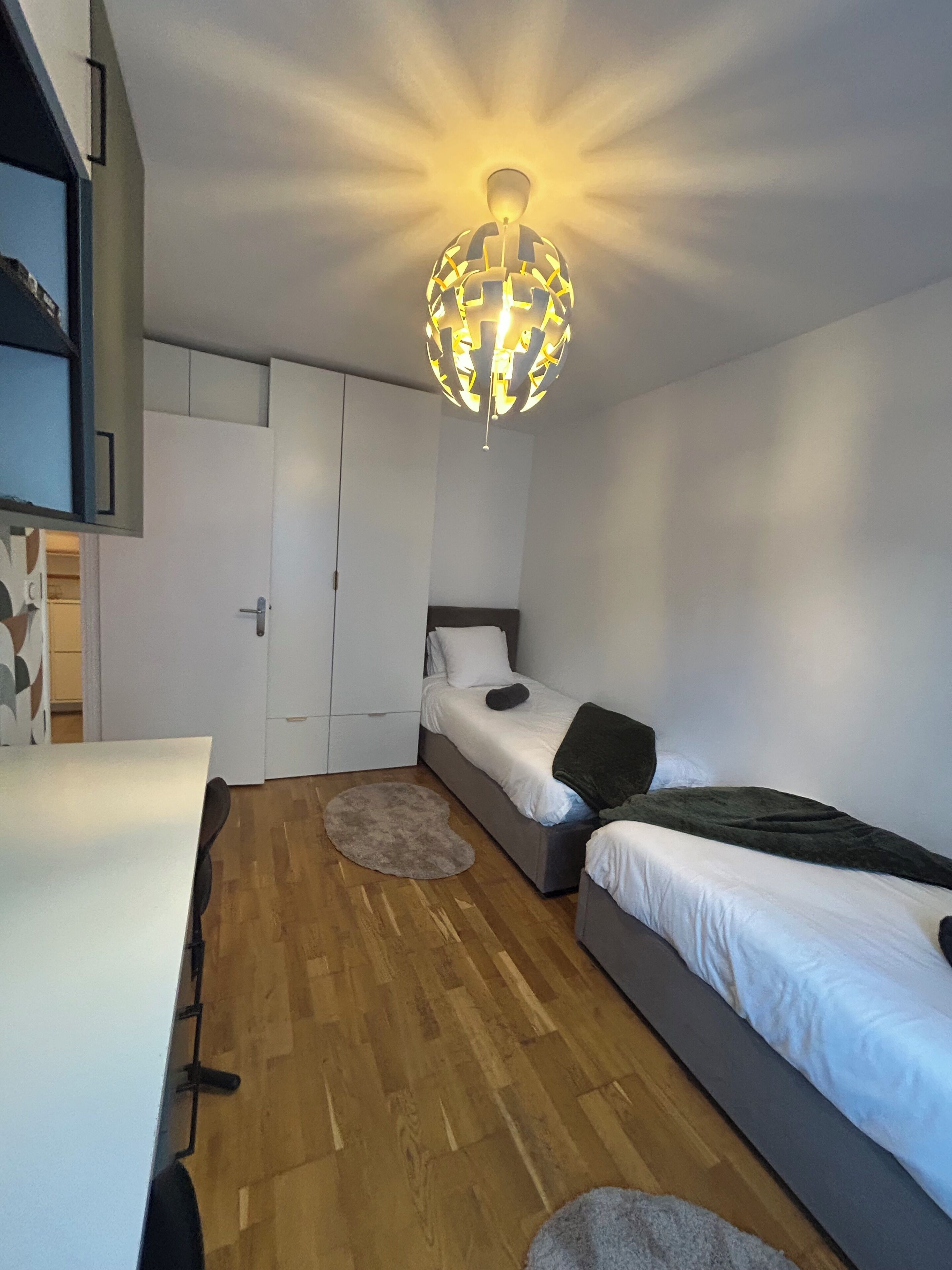 Ein kleines Zimmer mit Bett, Schreibtisch und Kleiderschrank.