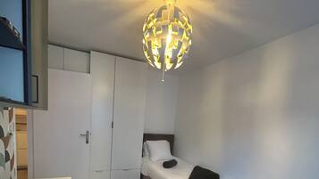 Ein kleines Zimmer mit Bett, Schreibtisch und Kleiderschrank.