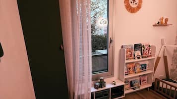 Una habitación infantil con ventana, estantería, alfombra con tema de león y decoración en la pared.