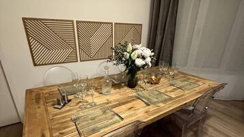 Ein Esstisch mit klarem Glas und einer Blumenvase, umgeben von klaren Stühlen in einem Raum mit Holzboden und dekorativen Wandverkleidungen.