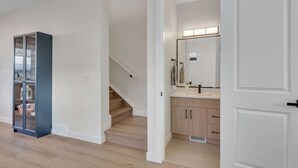 Um interior moderno com escada, armário de vidro e banheiro com toucador e espelho.