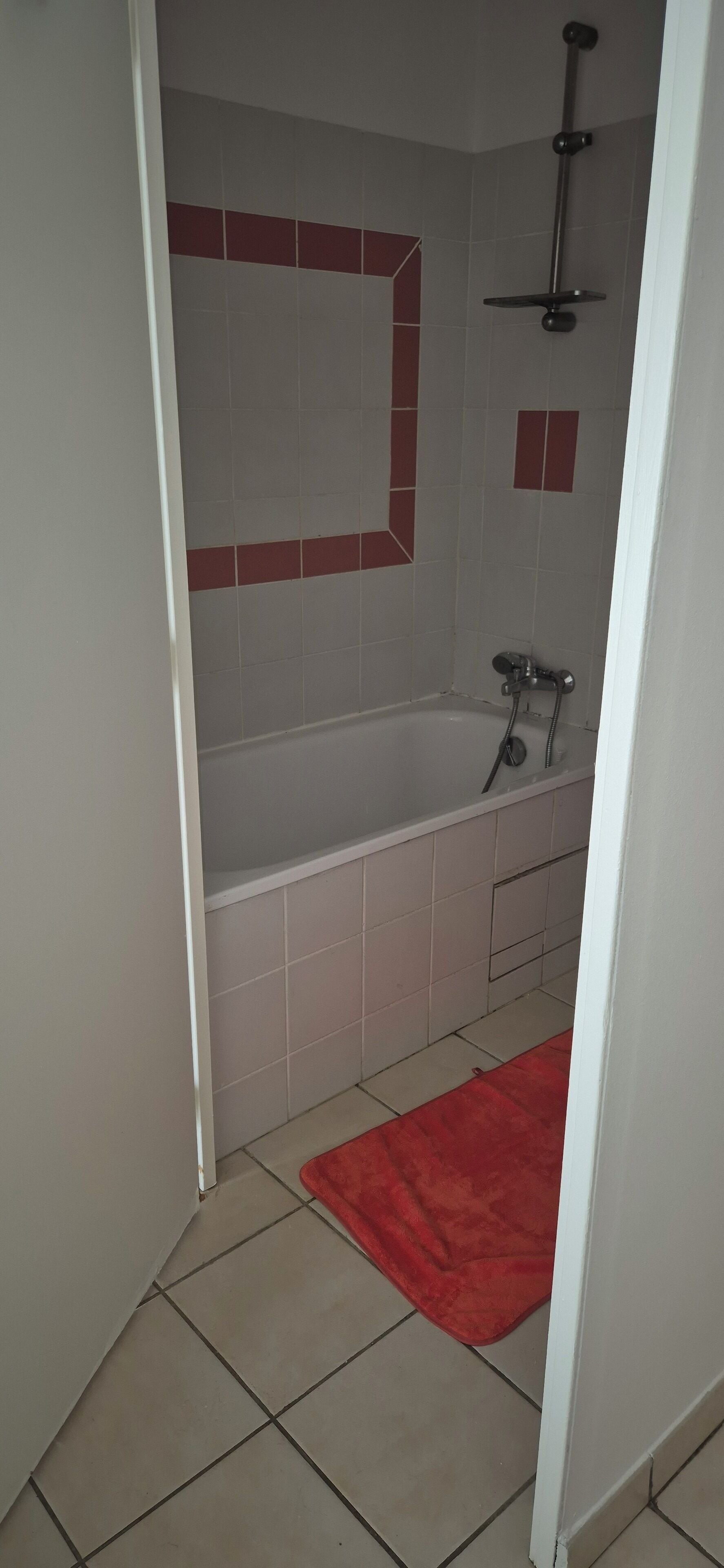 A bathroom with a bathtub, a shower, and a red rug.