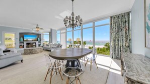 A spacious living room with a large TV, a fireplace, and a dining area with a view of the ocean. - Sterling Reef 301 (Panama City Beach)