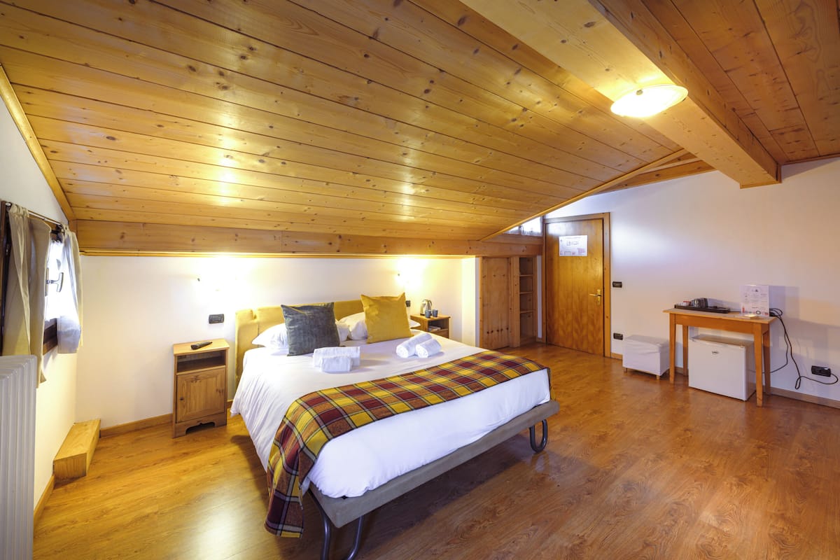 A bedroom with a bed, bedside tables, a desk, and a radiator.