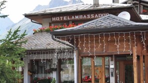 A hotel with a mountain view, wooden exterior, and flower boxes. - Hotel Ambassador Bormio (Bormio)