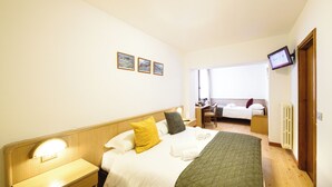 A hotel room with a bed, bedside table, and a desk with a chair. - Hotel Ambassador Bormio (Bormio)