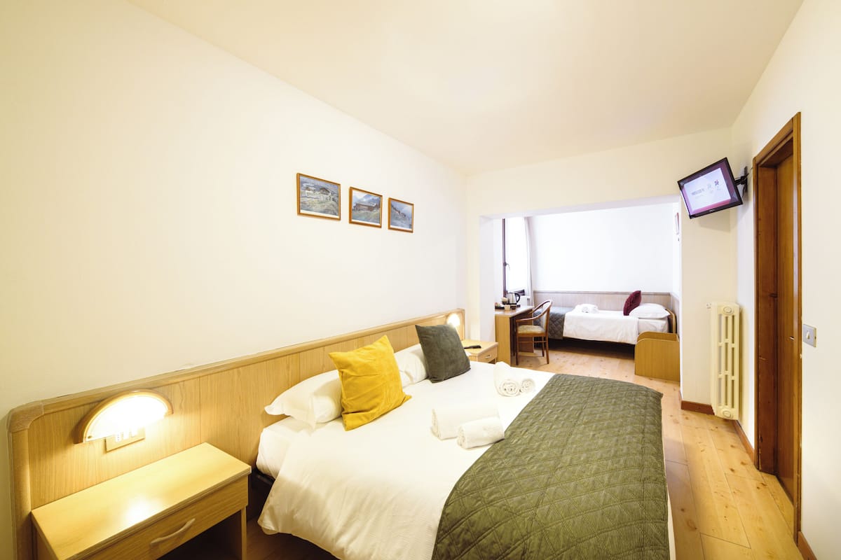 A hotel room with a bed, bedside table, and a desk with a chair.