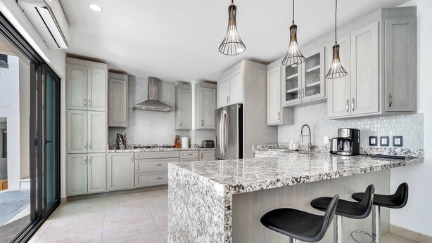 A modern kitchen with granite countertops, stainless steel appliances, and pendant lighting. - @ Marbella Lane – Grand Private Luxury Home Villa (Cabo Bello)