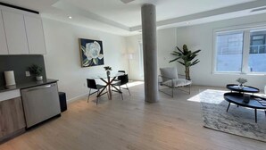 A spacious living area with a dining table, chairs, a coffee table, and a large plant. - Bright, warm & spotless 1 BR in North End Halifax (Halifax)