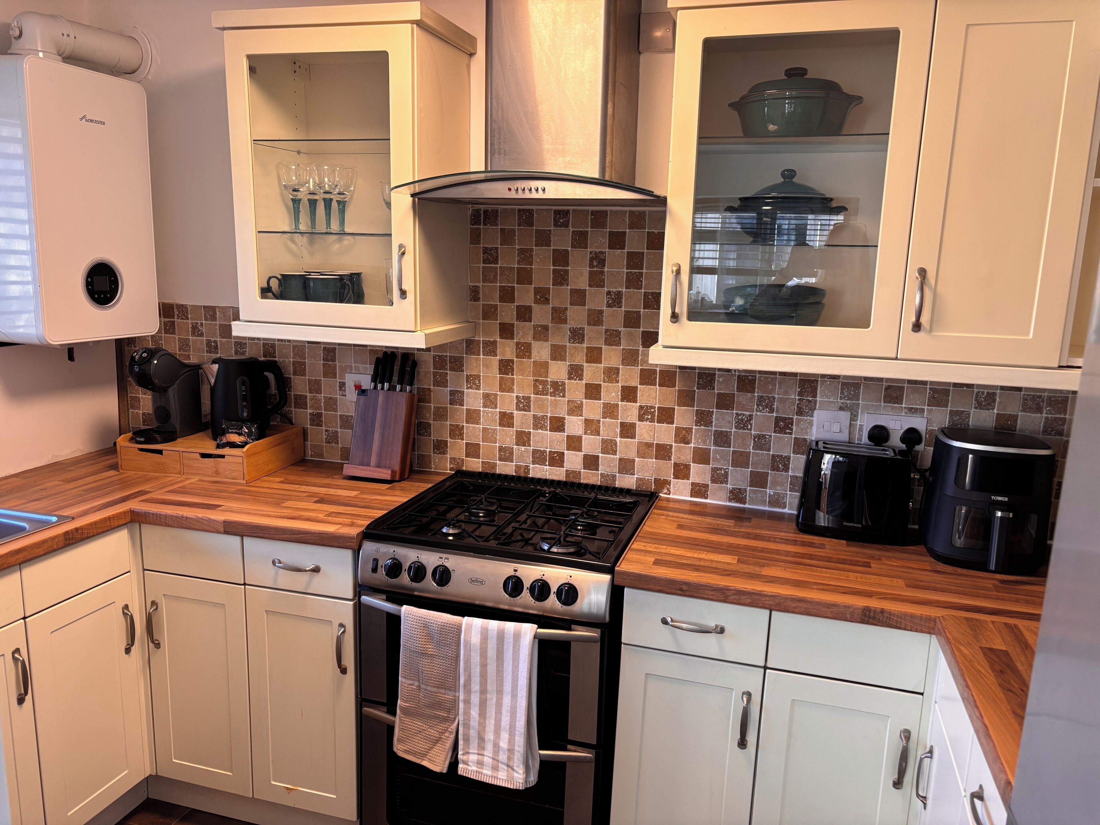 A kitchen with a gas stove, oven, white cabinets, a coffee maker, and a toaster.
