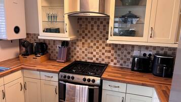 A kitchen with a gas stove, oven, white cabinets, a coffee maker, and a toaster.